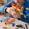 A hand holds a red and yellow building block toy pistol with shell ejecting action, surrounded by various plastic components.