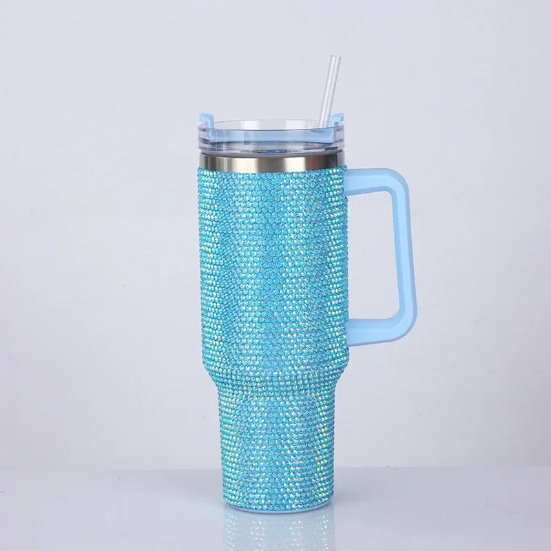 A bright blue rhinestone tumbler with a clear lid and straw, featuring a handle.