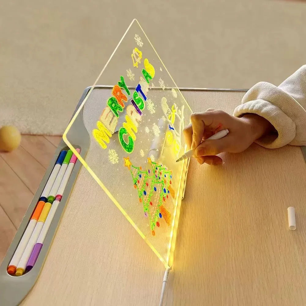 A hand writes Merry Christmas on a glowing LED drawing board with colored pens.