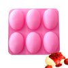 A pink silicone mold tray with six hemispherical molds and a strawberry garnish.