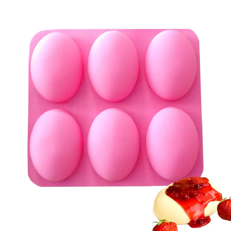 A pink silicone mold tray with six hemispherical molds and a strawberry garnish.
