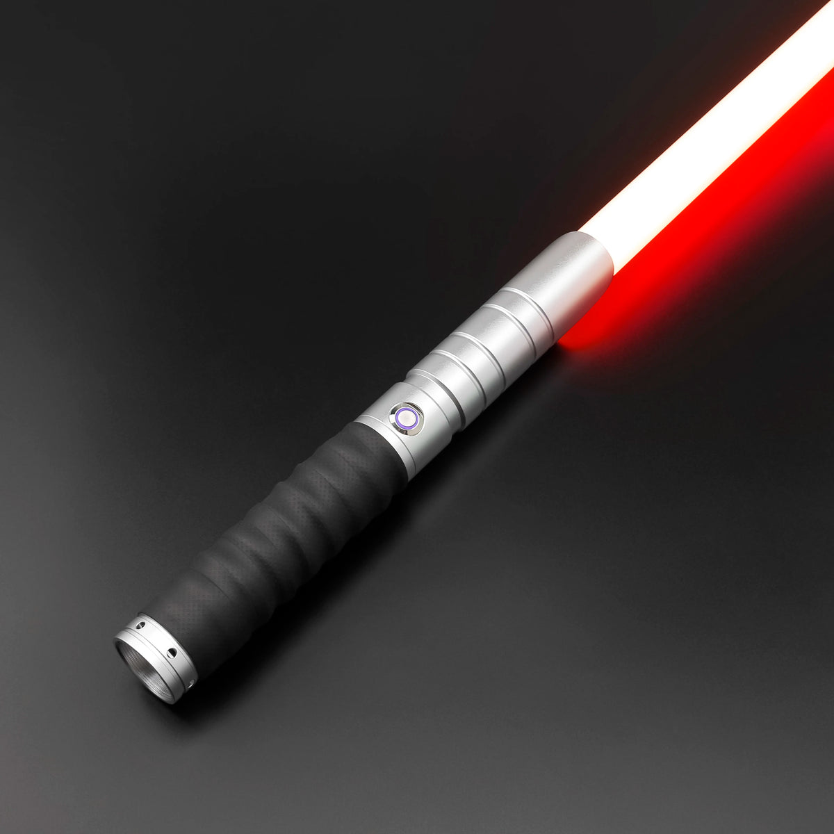 A close-up view of a silver lightsaber with a red blade and a black grip, illuminated against a dark background.