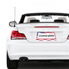 A white car with a license plate frame displaying the American flag design on the rear bumper.