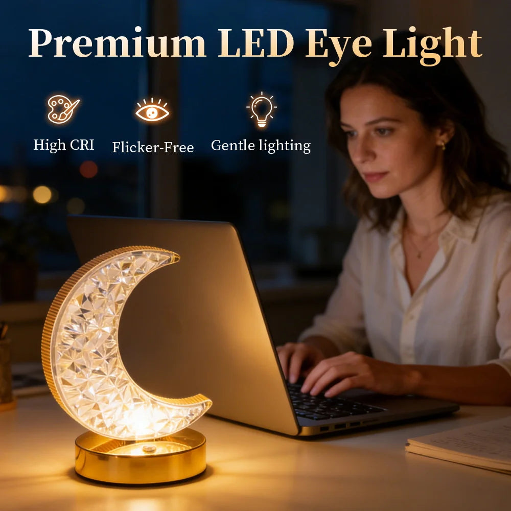 A woman works on a laptop illuminated by a crystal star moon night light.