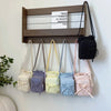 A collection of light-colored and pastel fabric crossbody bags hanging on a wooden shelf.