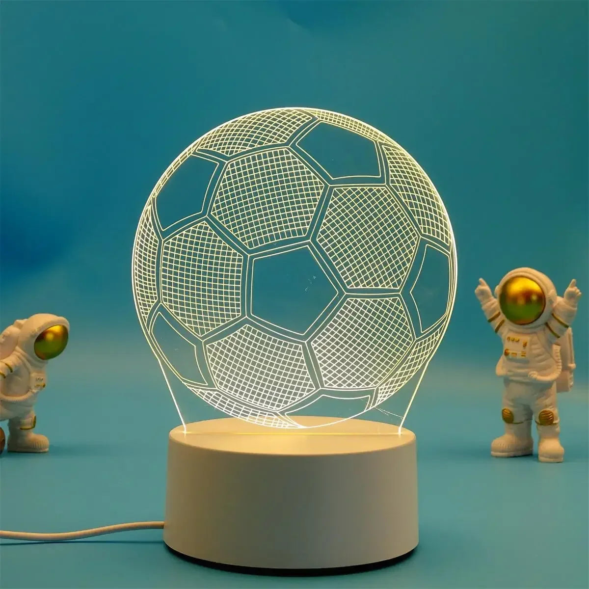 A glowing wireframe soccer ball is suspended above a white base, with small astronaut figures in the background.