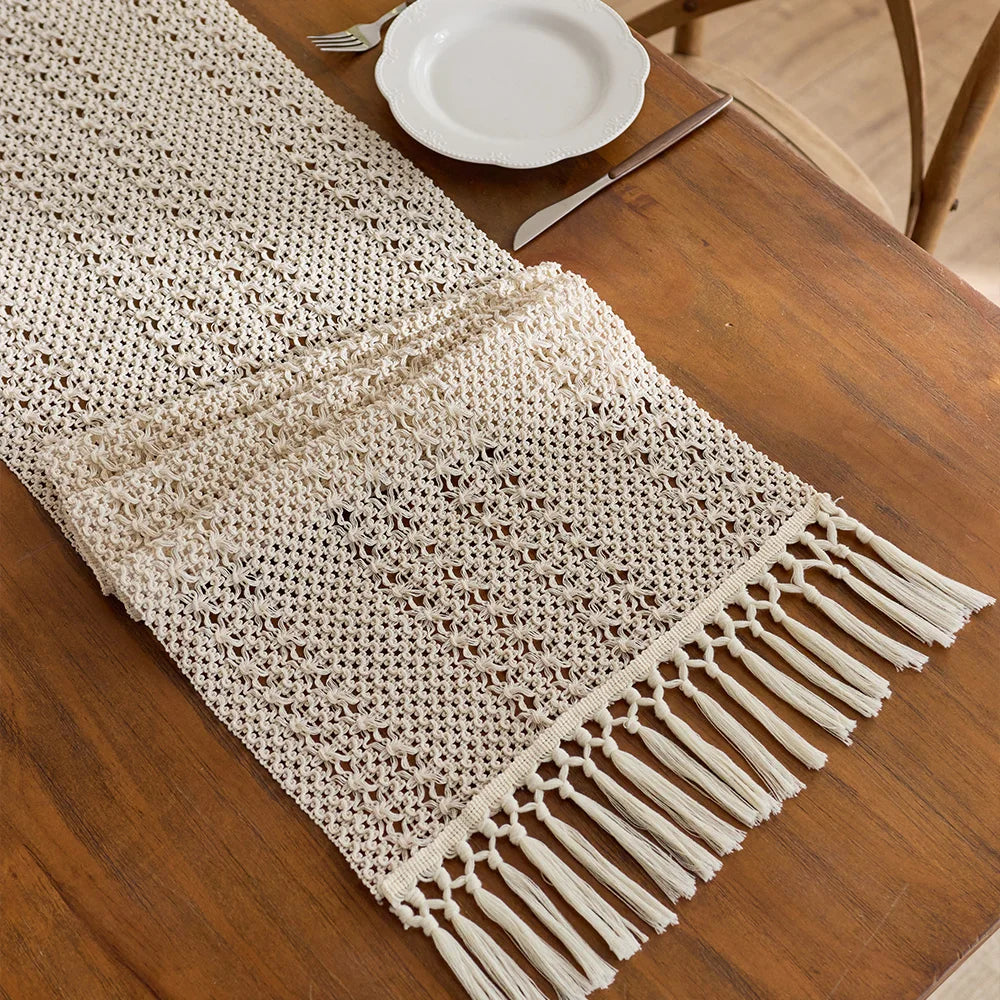 Beige boho table runner with tassels hand-woven farmhouse style placed on a wooden table.