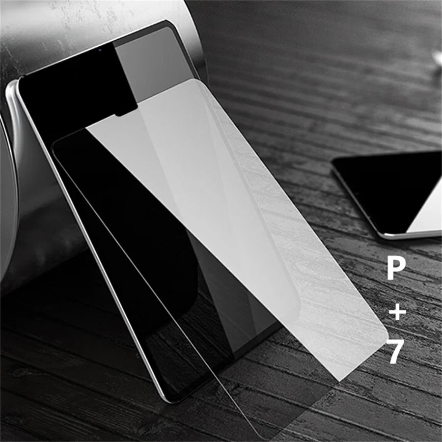 A close-up of a tempered glass screen protector for an iPad is shown on a wooden surface, with labels P, +, and 7 visible.