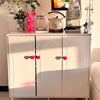 A white cabinet displaying a pink heart-shaped toilet flush button and various kitchen gadgets.