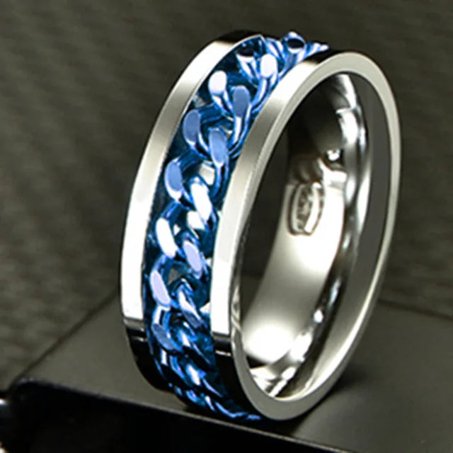 A close-up of a stainless steel spinner ring with a blue, textured band shown on a dark surface.