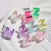 A collection of clear acrylic alphabet beads in various colors and sizes arranged on a white plate.