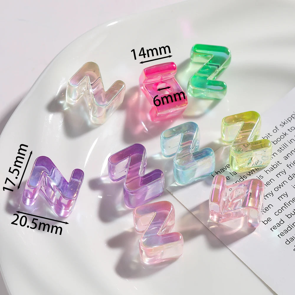 A collection of clear acrylic alphabet beads in various colors and sizes arranged on a white plate.
