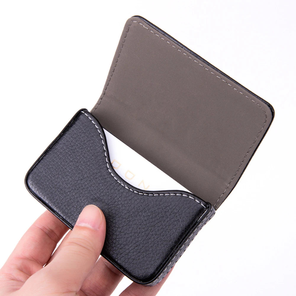 A hand holds a dark gray stitched PU leather card holder wallet with a black cover.
