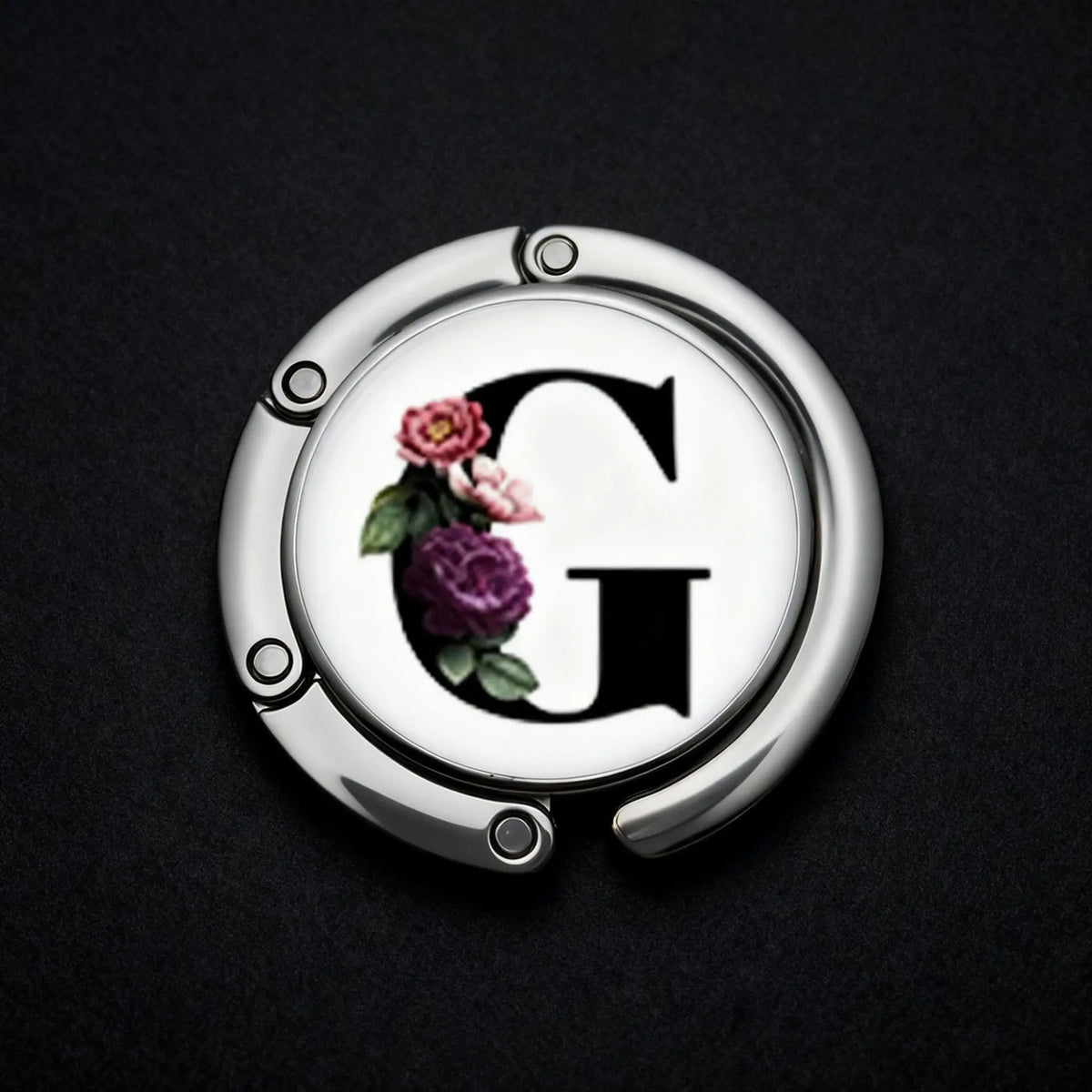 Silberner Briefhaken mit einem geschnitzten Initial G, umgeben von kleinen rosa und lila Blumen