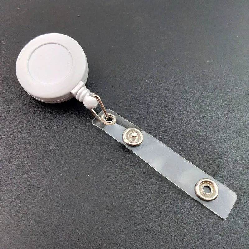 A silver badge reel with a white circular holder and a clear plastic strap.