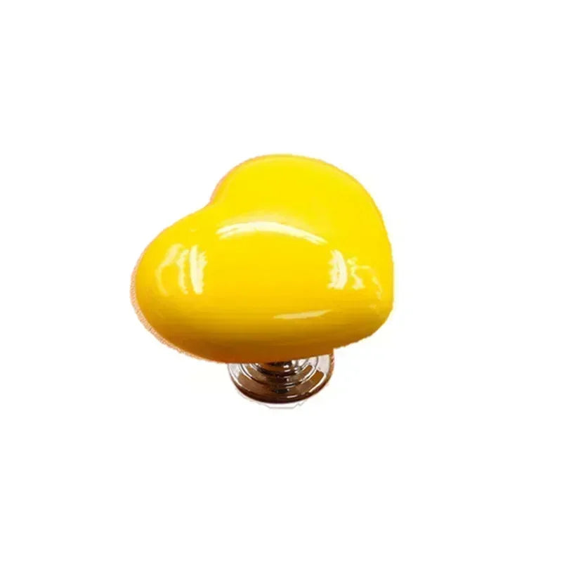 Yellow heart-shaped toilet flush button with a nail protector.