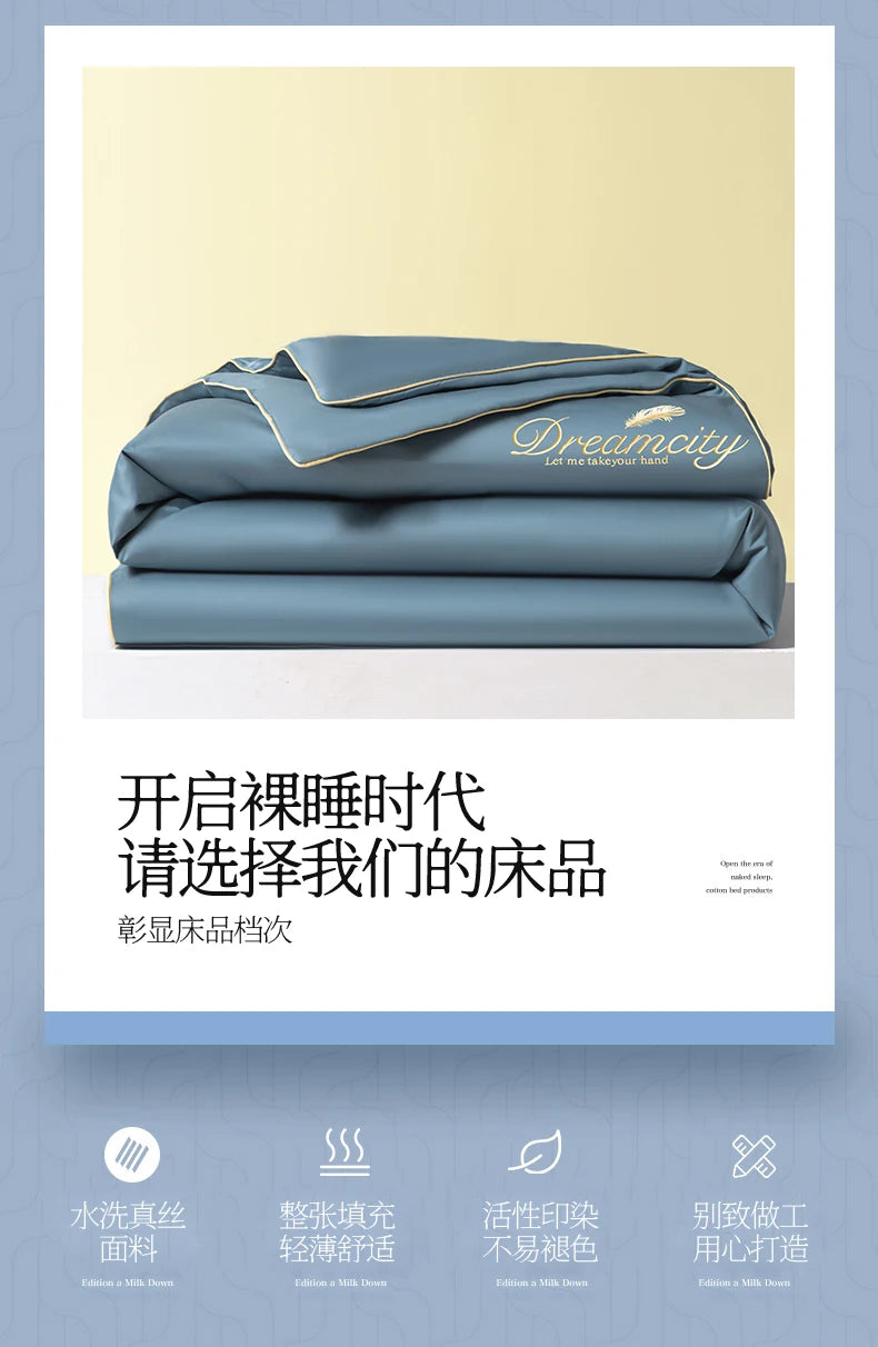 A stack of light blue comforters with gold embroidery, featuring the Dreamcity brand.