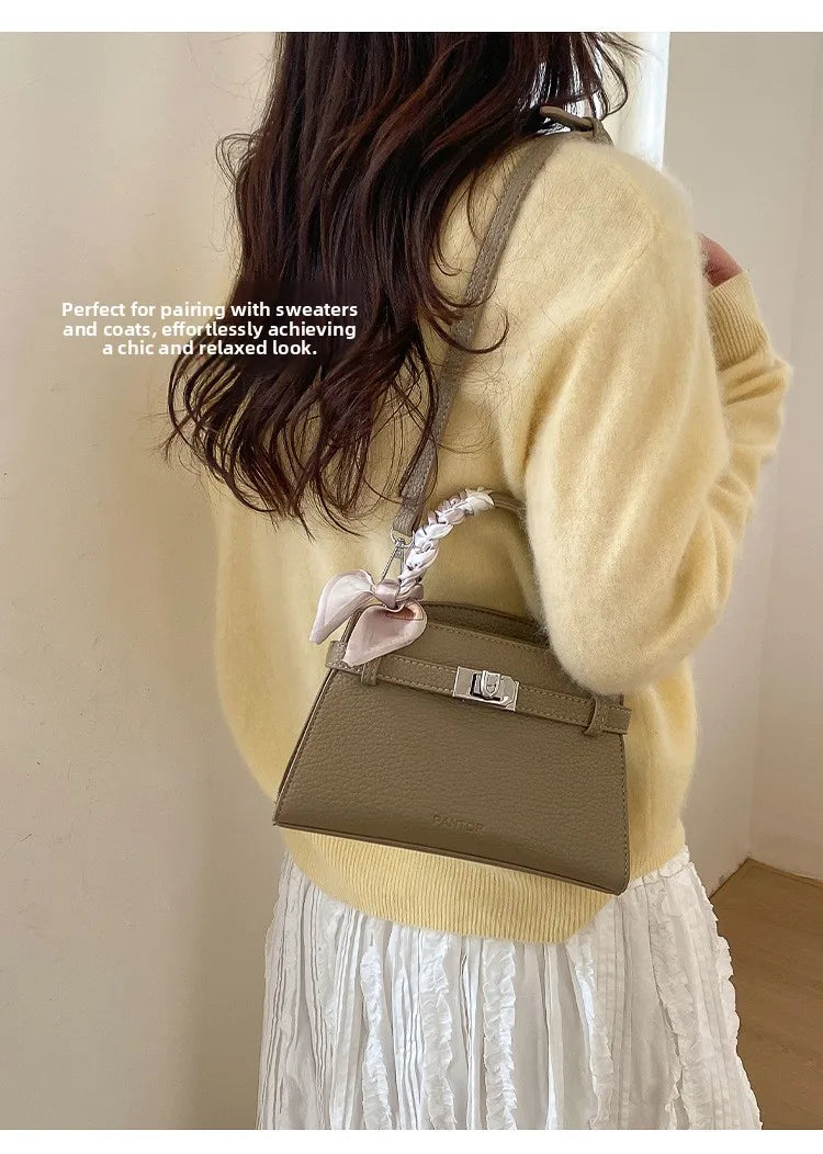 Eine Frau modelliert eine elegante braune Kunstleder-Clutchtasche mit einem cremefarbenen Pullover und einem weißen Rock.