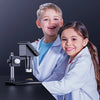 Two children smiling while holding a digital microscope for educational purposes.