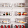 A display of clear microwave splatter covers with heat-resistant handles, holding various food items on a white shelf.