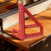 A red drawing line ruler is placed on a wooden workbench next to a metal measuring machine.