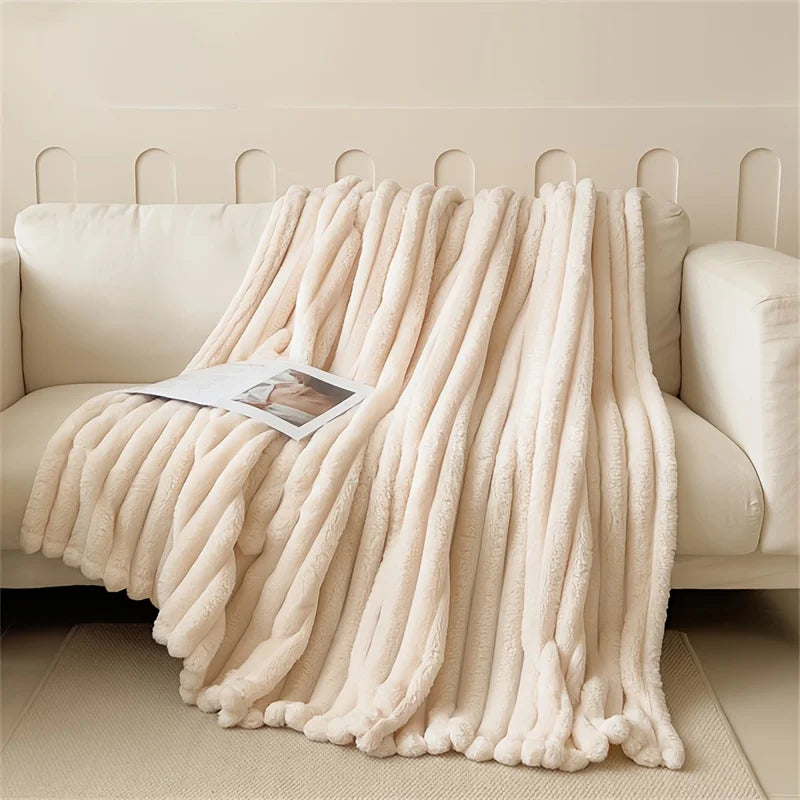 A fluffy beige flannel blanket draped over a light-colored sofa.