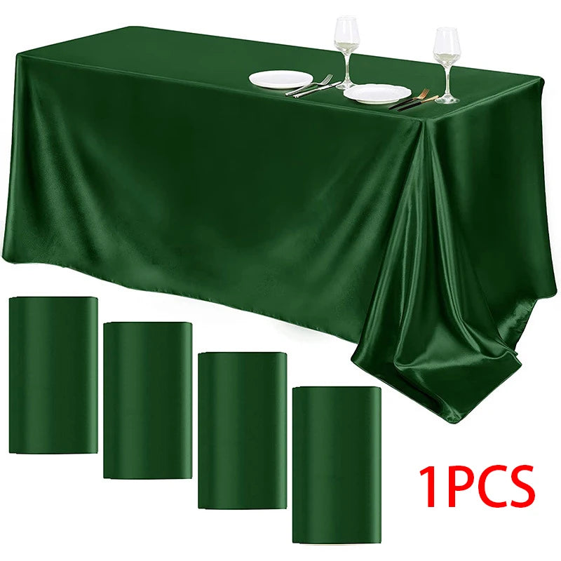 A dark emerald green satin tablecloth draped on a table with silverware and wine glasses set for dining.