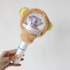 A hand holds a plush bear-themed cover for a SEVENTEEN official light stick, featuring soft brown fur and a clear dome with a