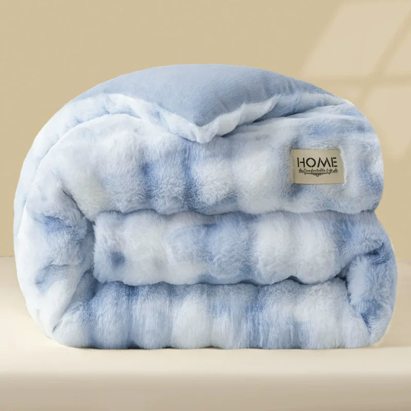 A thick, light blue plush winter comforter or quilt folded neatly on a surface.
