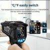 A hand holds a black digital infrared thermometer displaying temperature readings in both Celsius and Fahrenheit.