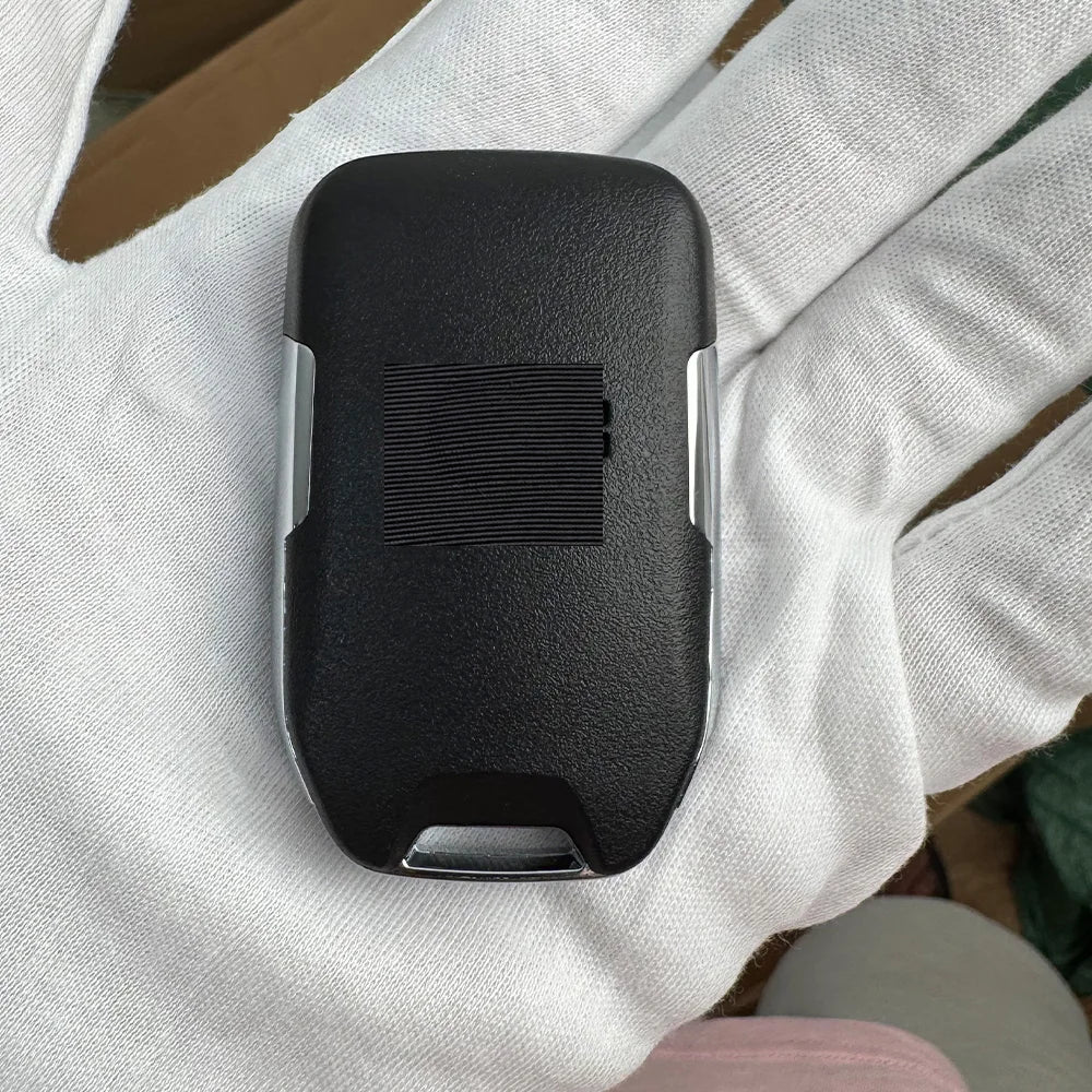 A black replacement remote key is held in a person's hand against a white background.