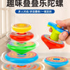 A stack of five colorful, layered spinning tops or gyros are displayed on a wooden surface.