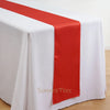 Elegant satin table runner in red and white draped over a white tablecloth.