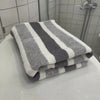 A stack of gray and white striped quick-dry bath towels resting on a white surface.