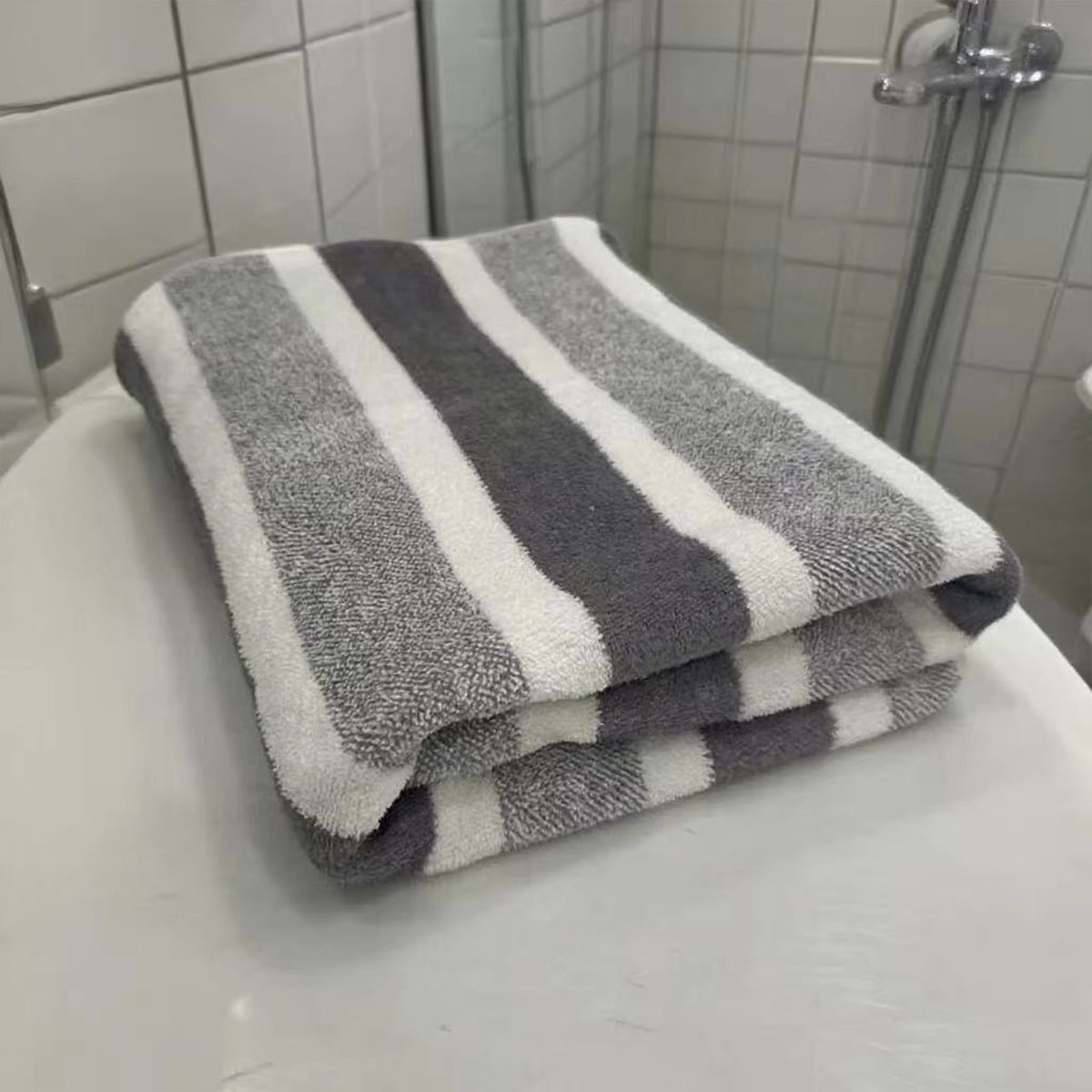 A stack of gray and white striped quick-dry bath towels resting on a white surface.