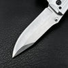 A folding pocket knife with a stainless steel blade and a visible silver blade edge resting on black leather.