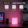 A pink touch-activated LED night light is displayed on a dark surface next to a laptop and a speaker.