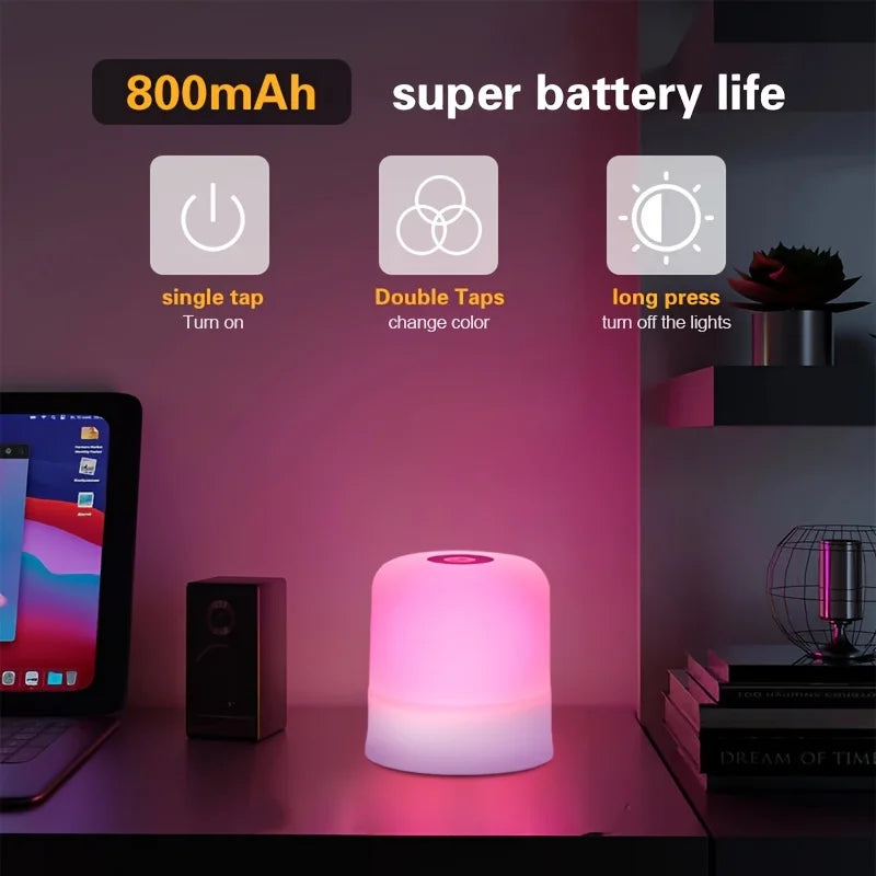 A pink touch-activated LED night light is displayed on a dark surface next to a laptop and a speaker.