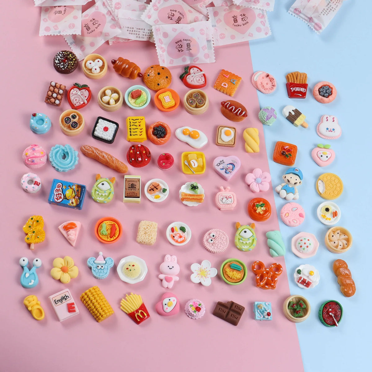 A collection of miniature resin food and drink figurines in various colors and shapes arranged on pink paper.