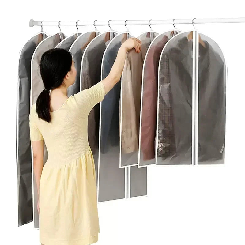 A woman is hanging transparent zippered garment storage bags on a rack.