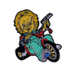 An enamel pin featuring Chucky the horror movie doll with a knife and a striped shirt.