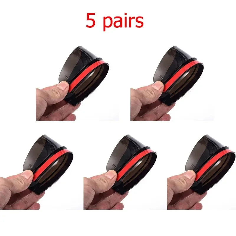 Five pairs of black carbon fiber car side mirror rain and sun visors being held by a hand.