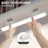Hands hold a white body sensor lamp with magnetic mounts, showing the light emitting from the strip.