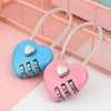 Pink heart-shaped padlock with a white cord and silver combination dial resting on a pink surface.