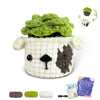 A finished crochet kit featuring a green textured animal, a small white animal, and yarn supplies.