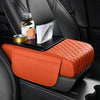 Orange quilted car armrest cushion with storage and cup holders placed on a black car seat.
