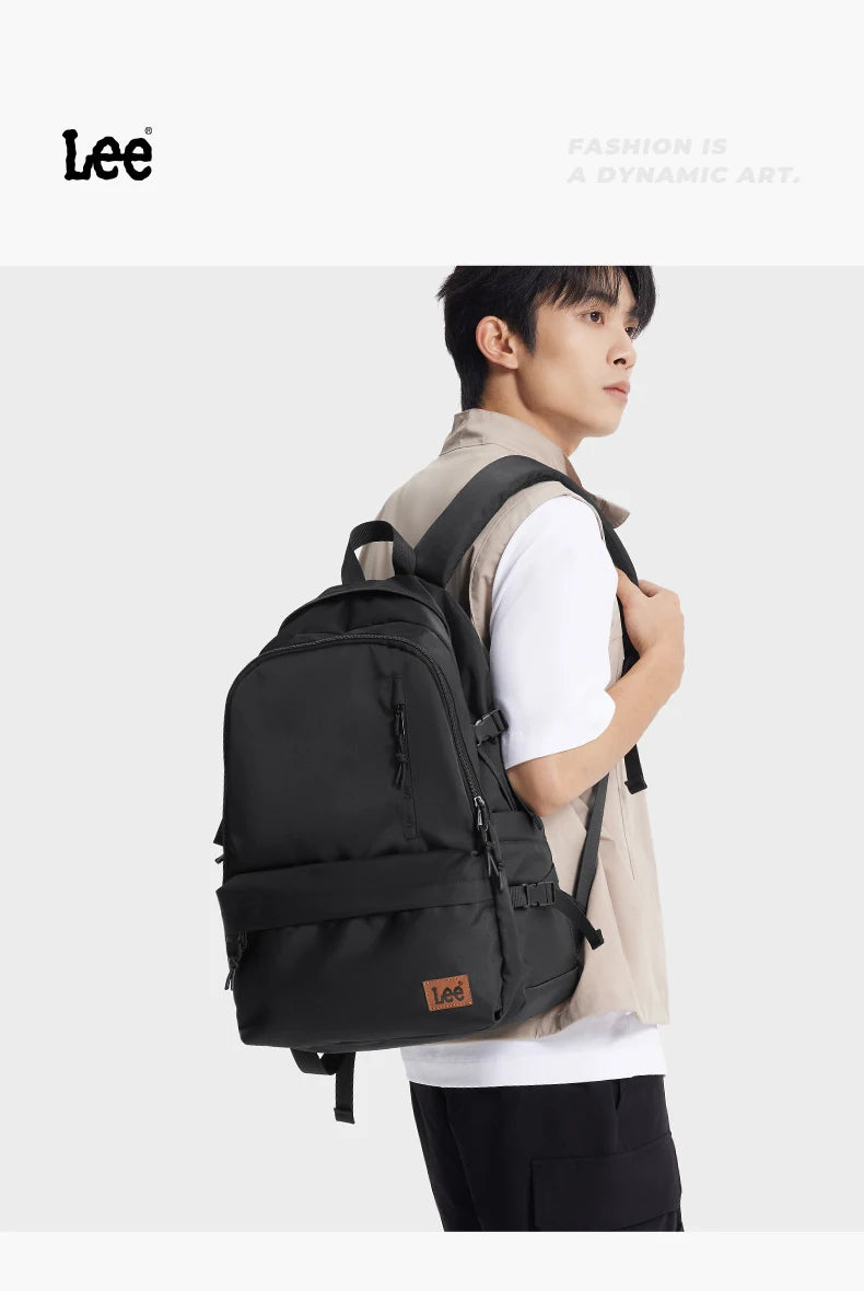 A man wearing a beige jacket and white shirt is carrying a black Lee ultralight water-resistant laptop backpack.
