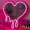 A neon sign shaped like a melting heart glows bright pink on a wall next to potted plants and decorative items.
