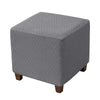 A gray stretch jacquard ottoman slipcover with an elastic edge.