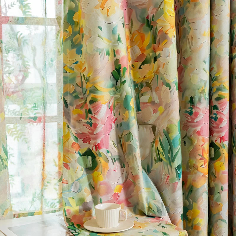 A close-up of a light floral plant pattern curtain panel in shades of yellow, pink, and green hanging next to a window.